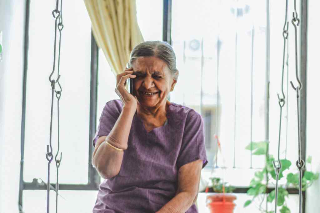 An older woman smiling as she talks on the telephone