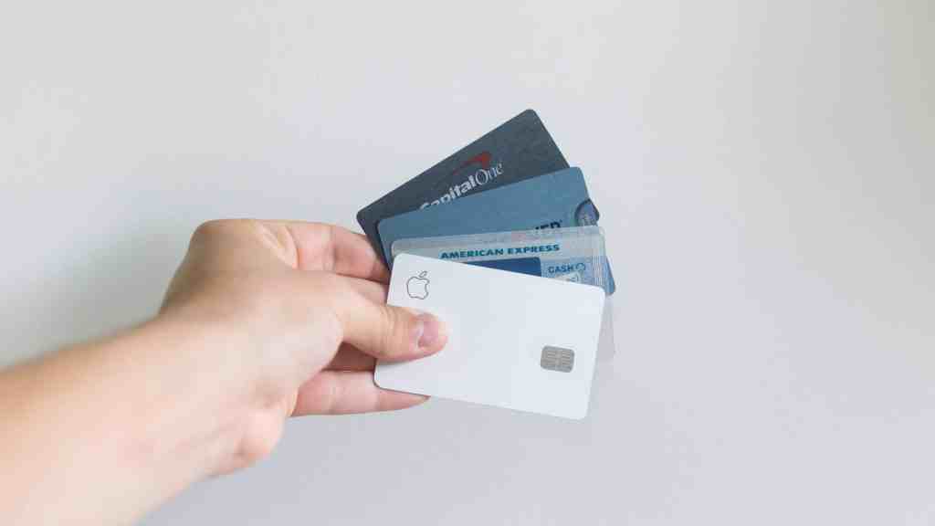 A hand holding four different types of credit cards