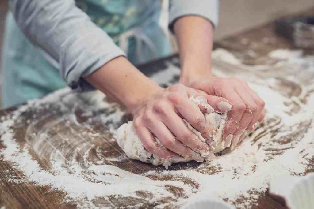 The hands of a baker as she kneads some dough