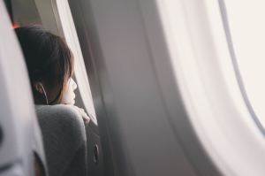 Side of woman's face looking out airplane window