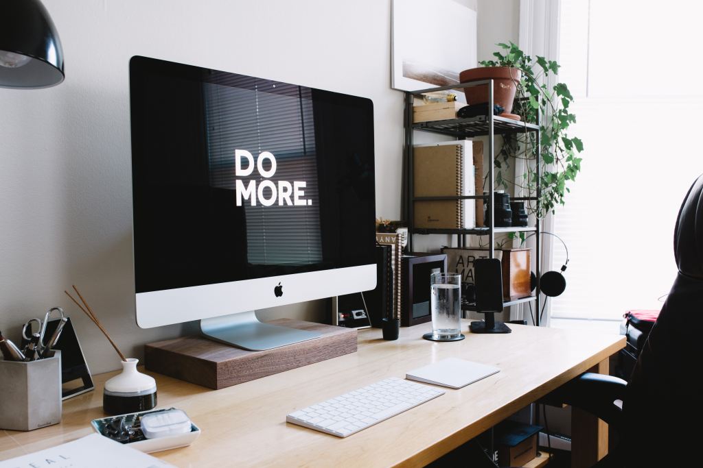 A desktop computer sitting on an organized desk with the words DO MORE on the screen