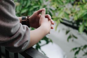 A person leaning on a ledge with their hands folded together