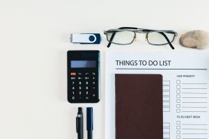 Glasses, calculator, pens, and to-do list all sitting organized