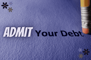 Admit Your Debt written on a piece of paper right next to an eraser