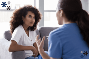 Two women sitting on a couch having a private conversation