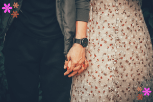 A person in a black outfit holding hands with a woman in a flowered dress