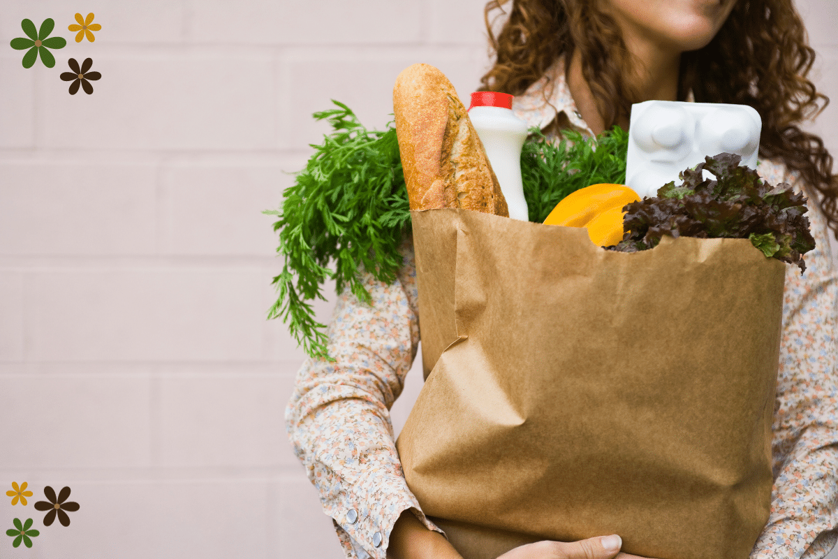A woman in a white long sleeve shirt holding a bag full of groceries