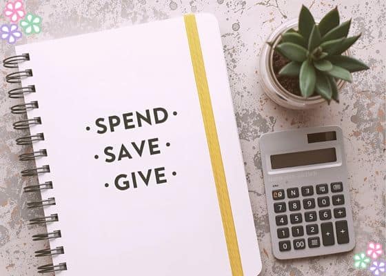 A notepad with the words spend save give on it next to a calculator and a small plant